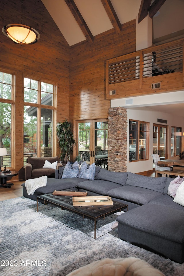 living room with french doors, beam ceiling, high vaulted ceiling, and wood walls