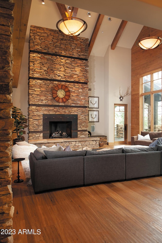 living room featuring hardwood / wood-style floors, a fireplace, high vaulted ceiling, and beamed ceiling