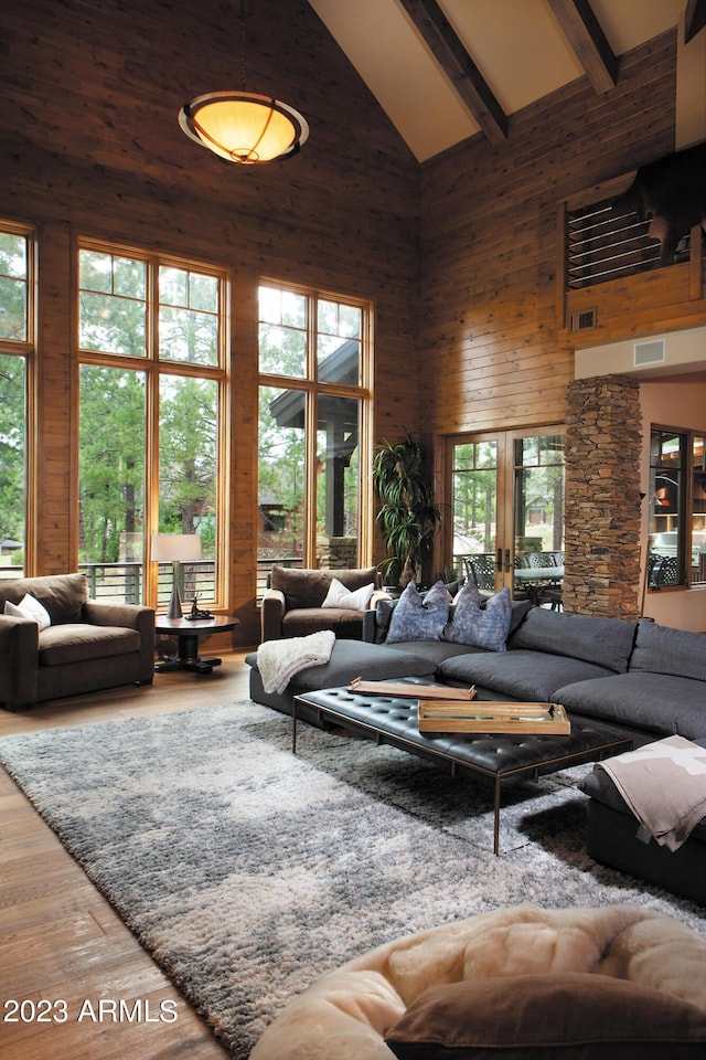 living room with beam ceiling, high vaulted ceiling, hardwood / wood-style floors, and wood walls