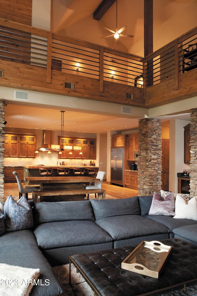 living room with beamed ceiling, a high ceiling, decorative columns, and ceiling fan