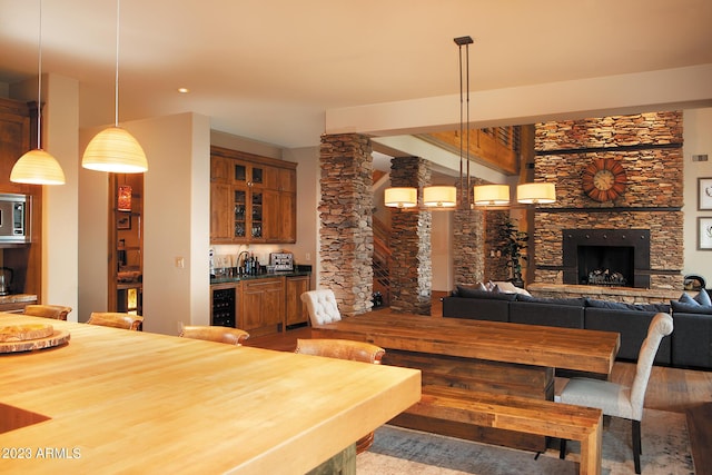 dining room featuring wood-type flooring, a stone fireplace, wine cooler, and indoor bar