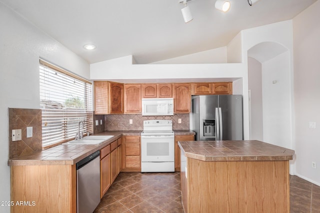 kitchen with tasteful backsplash, tile counters, appliances with stainless steel finishes, vaulted ceiling, and a sink