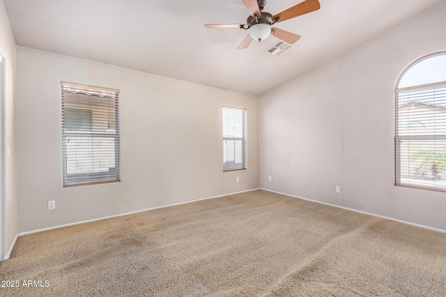 spare room featuring a ceiling fan, carpet flooring, visible vents, and a healthy amount of sunlight