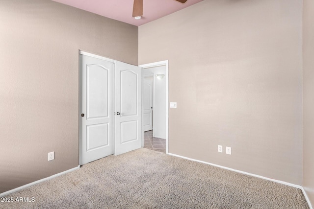 unfurnished bedroom with a ceiling fan, carpet, a closet, and baseboards