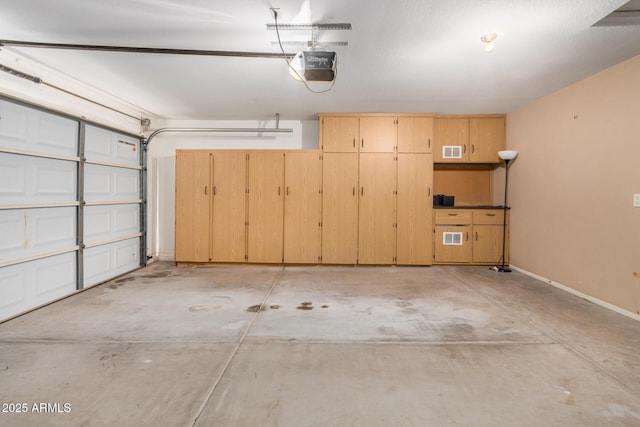 garage featuring baseboards, visible vents, and a garage door opener