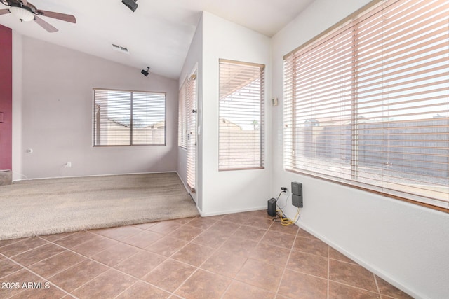 spare room featuring a ceiling fan, tile patterned flooring, visible vents, and vaulted ceiling