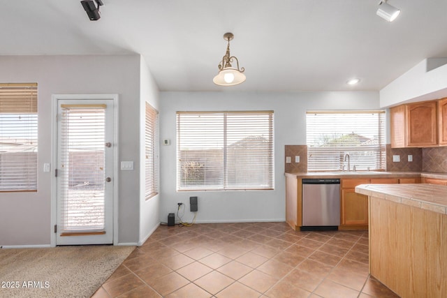 kitchen with light tile patterned floors, light countertops, decorative backsplash, a sink, and dishwasher