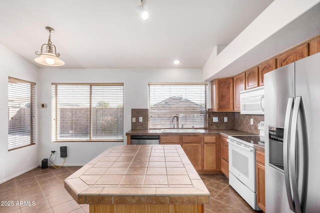 kitchen featuring tile countertops, a sink, appliances with stainless steel finishes, tile patterned floors, and tasteful backsplash