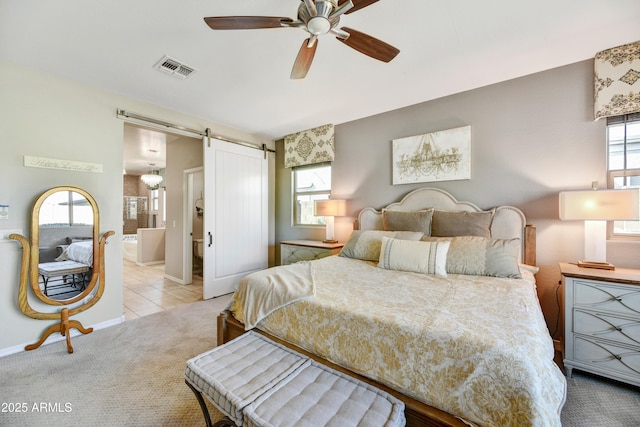 bedroom featuring light colored carpet, visible vents, a barn door, light tile patterned flooring, and baseboards