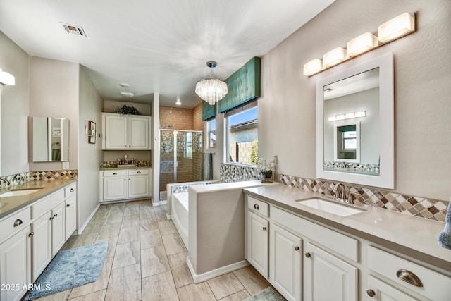 full bath featuring visible vents, two vanities, a sink, a shower stall, and a bath