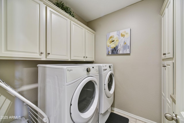 clothes washing area with washing machine and clothes dryer, cabinet space, and baseboards