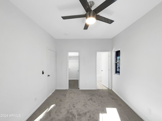 unfurnished bedroom featuring a spacious closet, light carpet, ceiling fan, and a closet