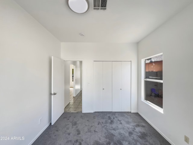 unfurnished bedroom with a closet and dark carpet