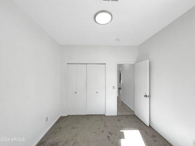 unfurnished bedroom with light carpet and a closet