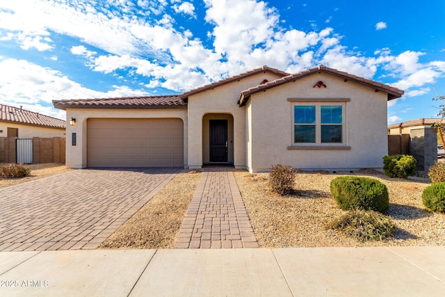 mediterranean / spanish house featuring decorative driveway, an attached garage, and stucco siding