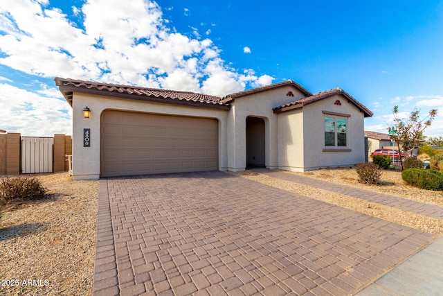 mediterranean / spanish-style house with decorative driveway, a tiled roof, an attached garage, and stucco siding