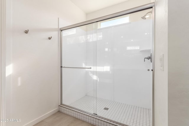 bathroom with a shower stall and baseboards