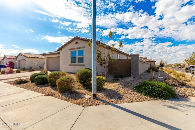 view of property exterior featuring an attached garage, driveway, a tile roof, and stucco siding