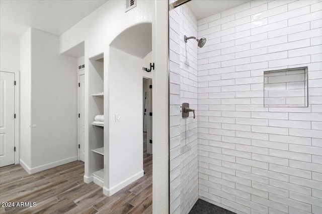 bathroom with tiled shower and hardwood / wood-style floors