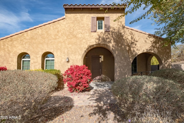 mediterranean / spanish house featuring a tiled roof and stucco siding