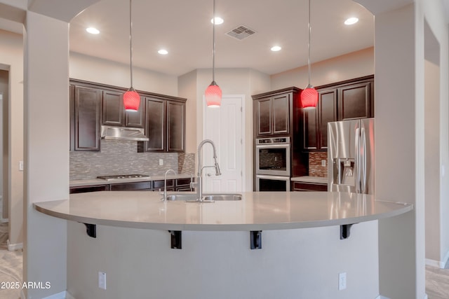 kitchen with a sink, visible vents, light countertops, appliances with stainless steel finishes, and pendant lighting