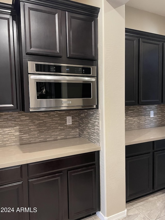 kitchen featuring light countertops, backsplash, and oven