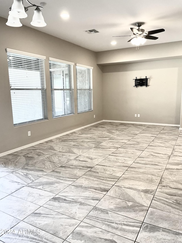 spare room featuring a ceiling fan, visible vents, and baseboards