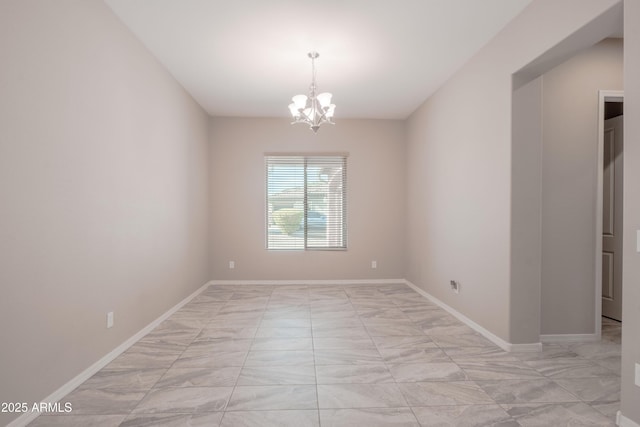 unfurnished room with baseboards and a chandelier