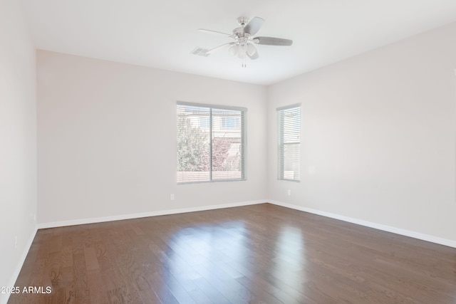 spare room featuring dark wood-style floors, visible vents, baseboards, and a ceiling fan