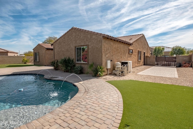 rear view of house with a patio, a fenced backyard, a tile roof, a fenced in pool, and stucco siding