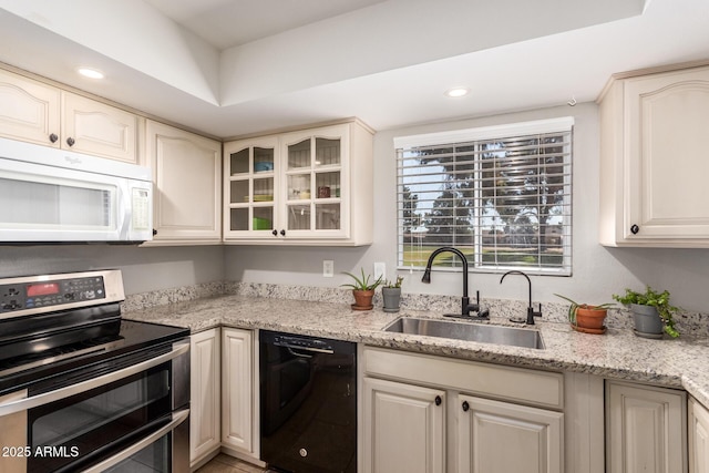 kitchen with sink, light stone counters, a tray ceiling, dishwasher, and range with two ovens