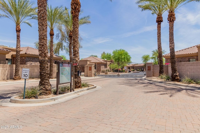 4241 N Pebblecreek Pkwy Unit 7, Goodyear, AZ 85395 - view of decorative road featuring a gate, a gated entry, curbs, and traffic signs