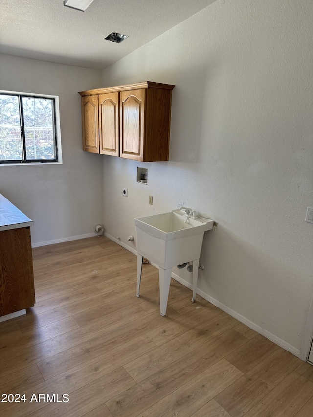 washroom featuring cabinets, washer hookup, electric dryer hookup, light hardwood / wood-style floors, and hookup for a gas dryer