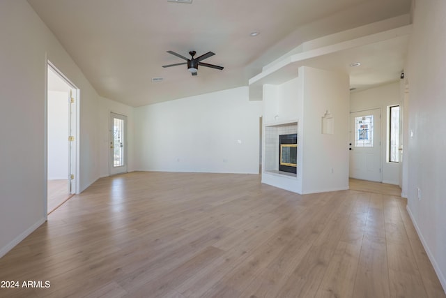 unfurnished living room featuring a tile fireplace, ceiling fan, and light hardwood / wood-style floors