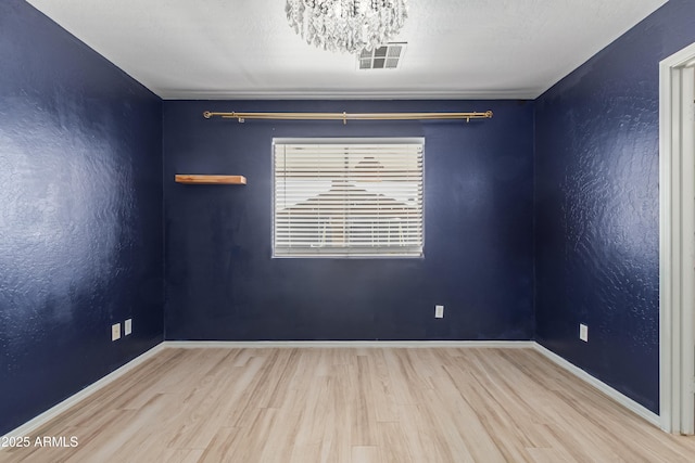 spare room with wood-type flooring and a notable chandelier