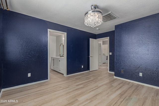 unfurnished bedroom with an inviting chandelier, light hardwood / wood-style flooring, and ensuite bathroom