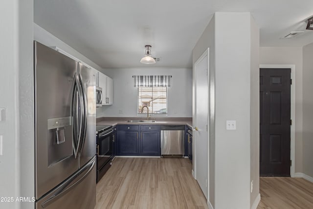 kitchen featuring blue cabinetry, sink, light wood-type flooring, and stainless steel appliances