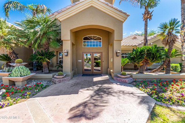 entrance to property featuring a tiled roof, stucco siding, and french doors