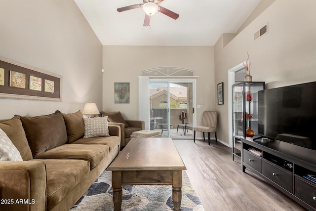 living area with visible vents, baseboards, vaulted ceiling, light wood-style floors, and a ceiling fan