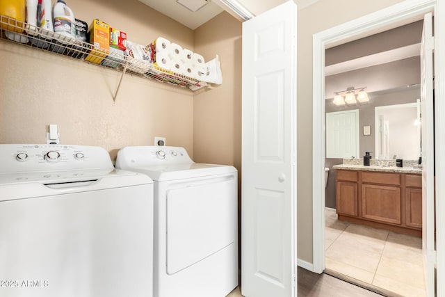 washroom with washer and dryer, laundry area, light tile patterned floors, and a sink