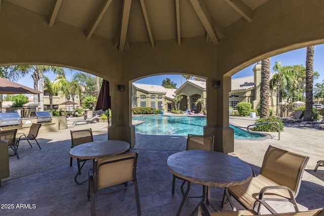 view of patio / terrace featuring outdoor dining area, a community pool, and area for grilling