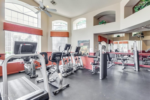 workout area featuring a ceiling fan, visible vents, and a towering ceiling