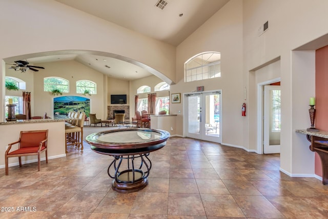 tiled foyer with a stone fireplace, baseboards, visible vents, and a ceiling fan