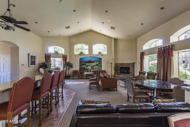 living area featuring plenty of natural light, arched walkways, visible vents, and high vaulted ceiling