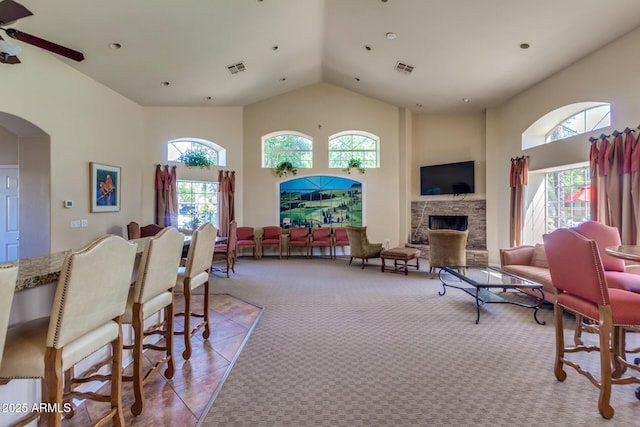 living area featuring a wealth of natural light, high vaulted ceiling, light colored carpet, and a fireplace