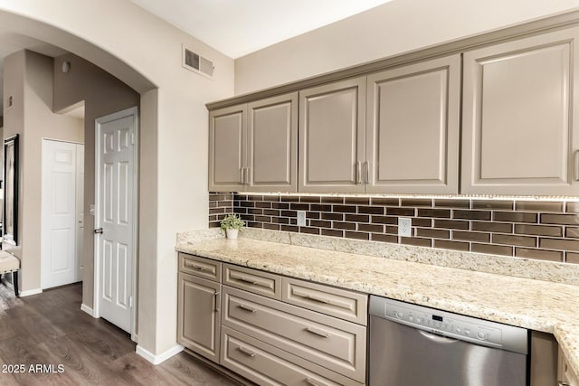 kitchen with backsplash, dark wood-type flooring, dishwasher, light stone counters, and arched walkways