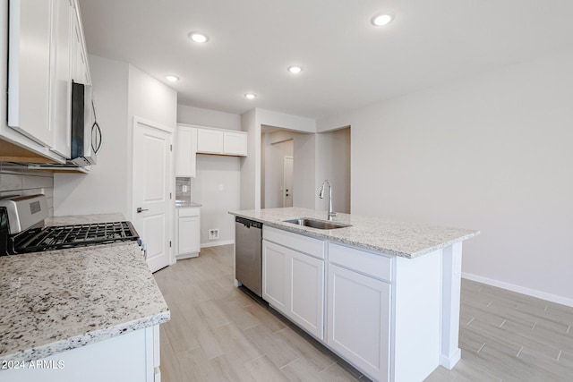 kitchen with white cabinets, a kitchen island with sink, sink, and appliances with stainless steel finishes