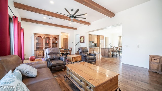 living room featuring beamed ceiling, ceiling fan, and dark hardwood / wood-style flooring