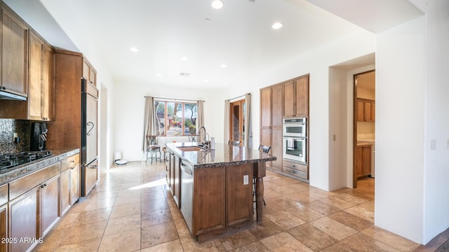 kitchen featuring tasteful backsplash, sink, a breakfast bar, stainless steel appliances, and a center island with sink