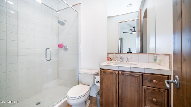 bathroom featuring vanity, toilet, ceiling fan, and a shower with door